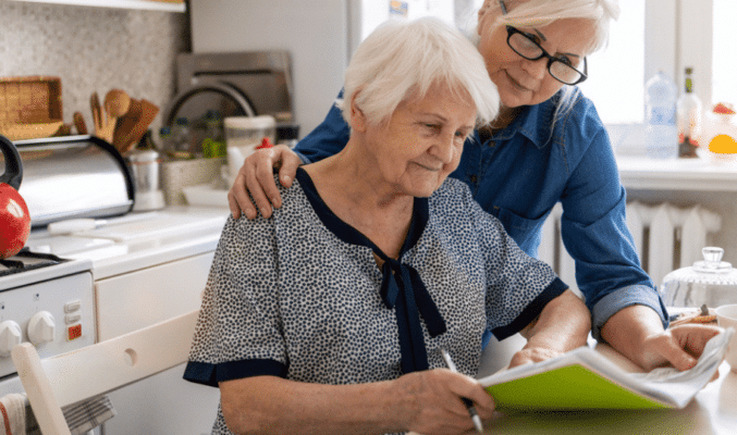Mature woman helping elderly mother with paperwork