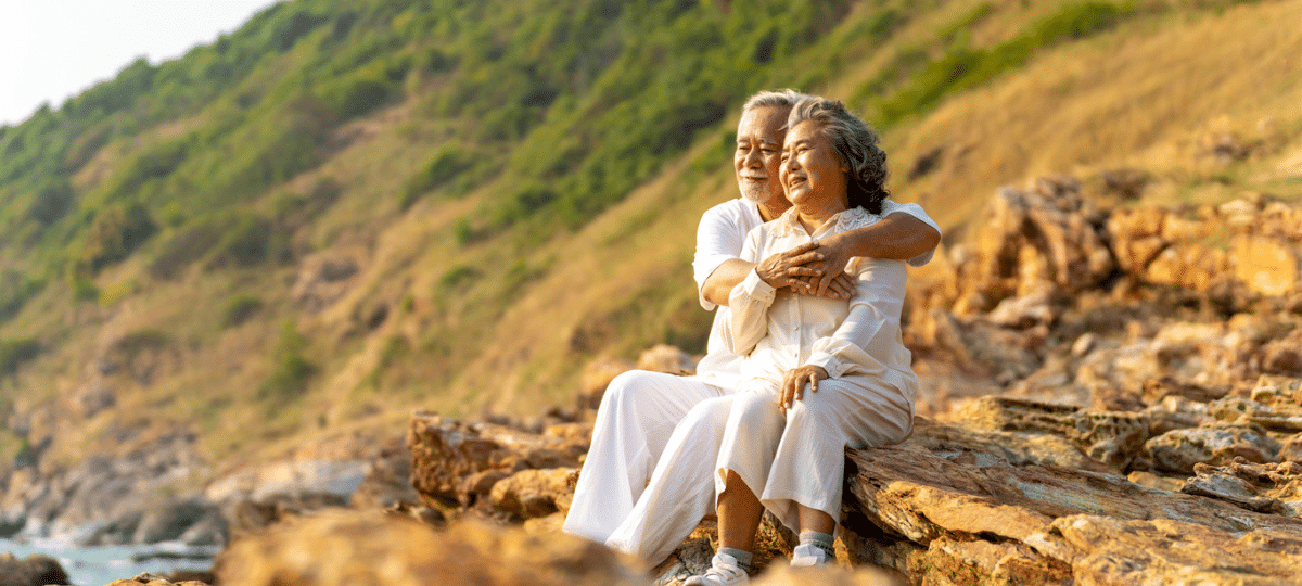 Older man and woman sitting on a cliff in nature