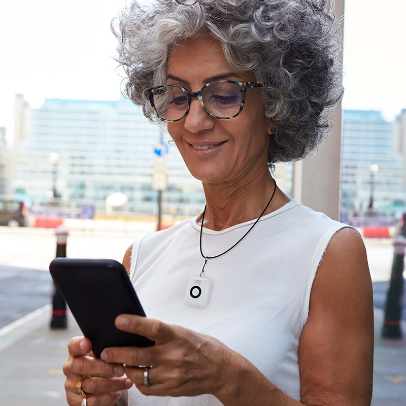 Woman using smartphone wearing Medical Alert Mini Mobile System pendant