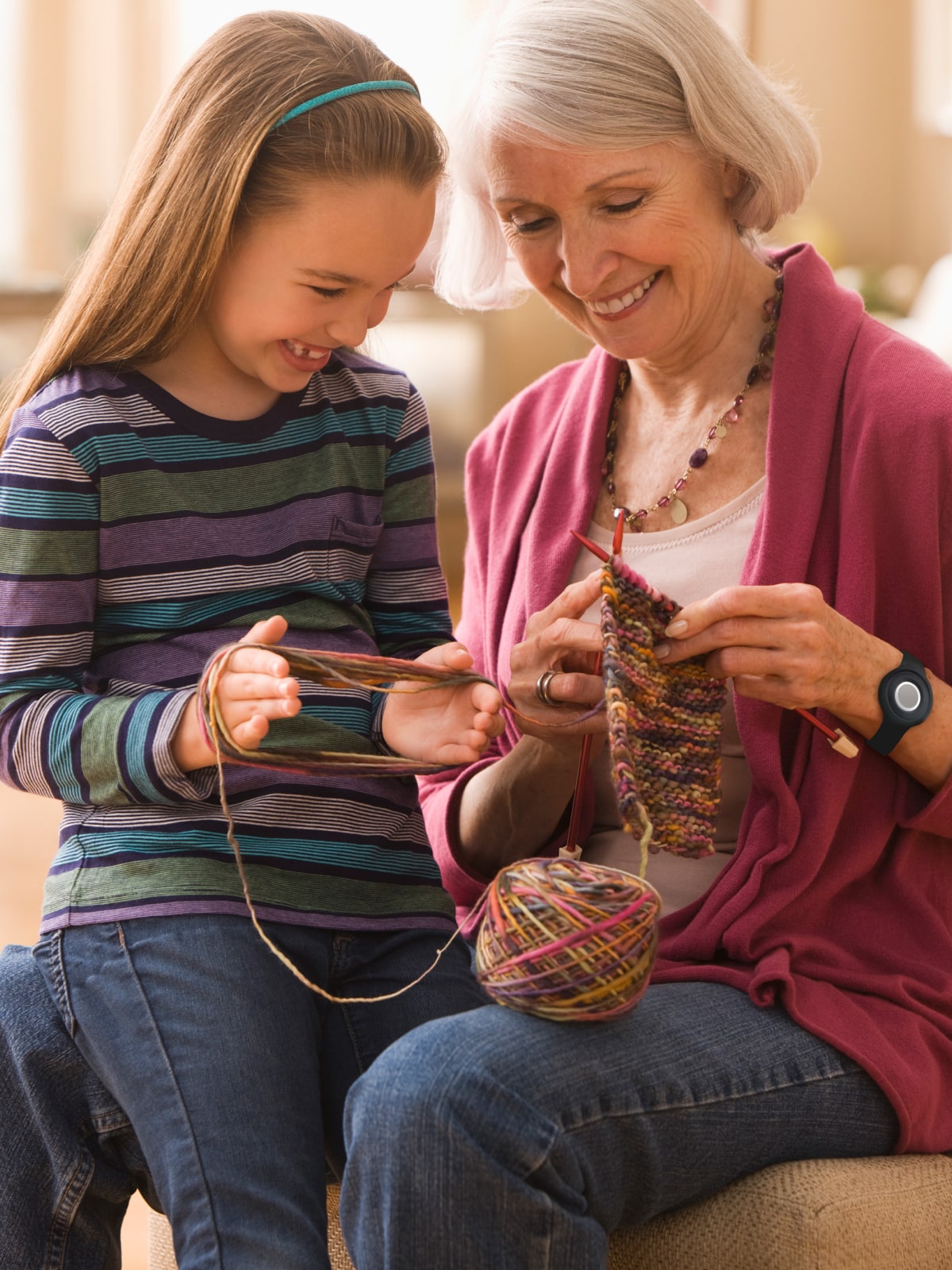 Woman wearing Medical Alert help button while knitting with her granddaughter