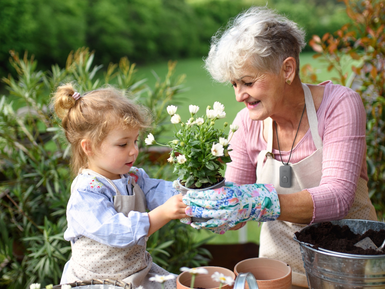 Woman wearing Medical Alert Mobile System while gardening with her granddaughter