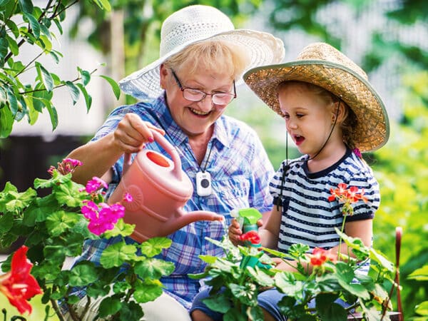 Grandmother wearing On the Go medical alert system in the garden with granddaughter