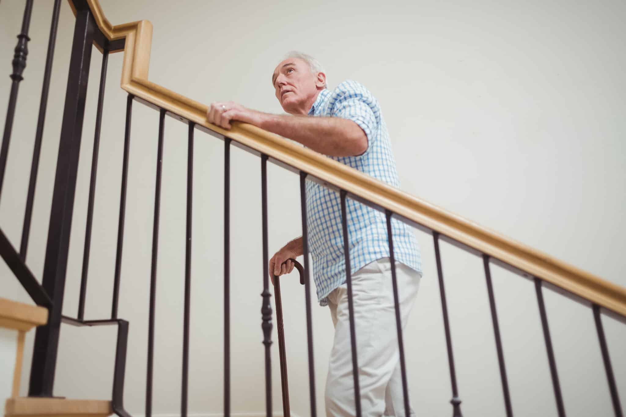 An older adult moving safely at home using a stair handrail