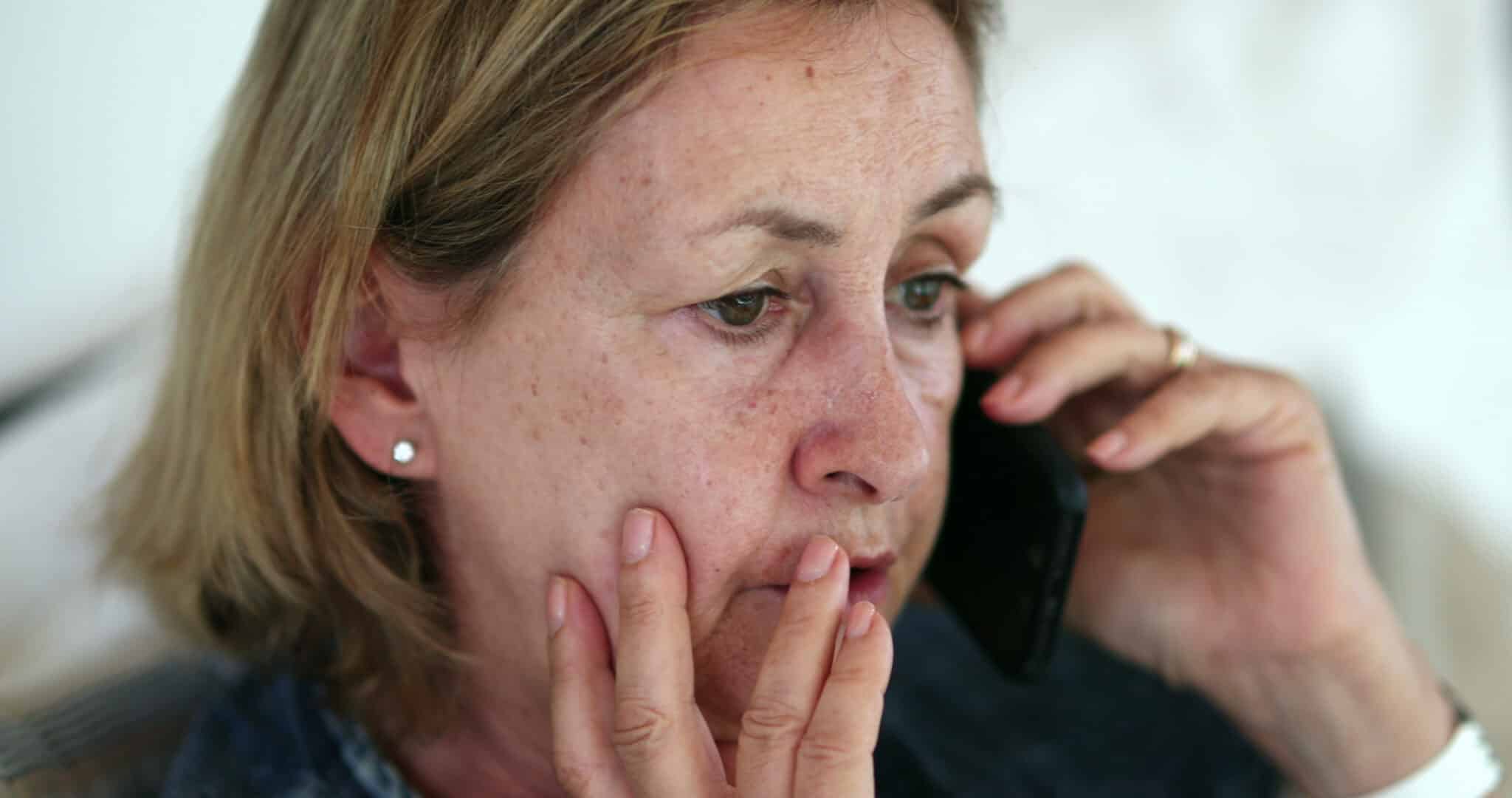 An older adult pausing to verify a suspicious phone call