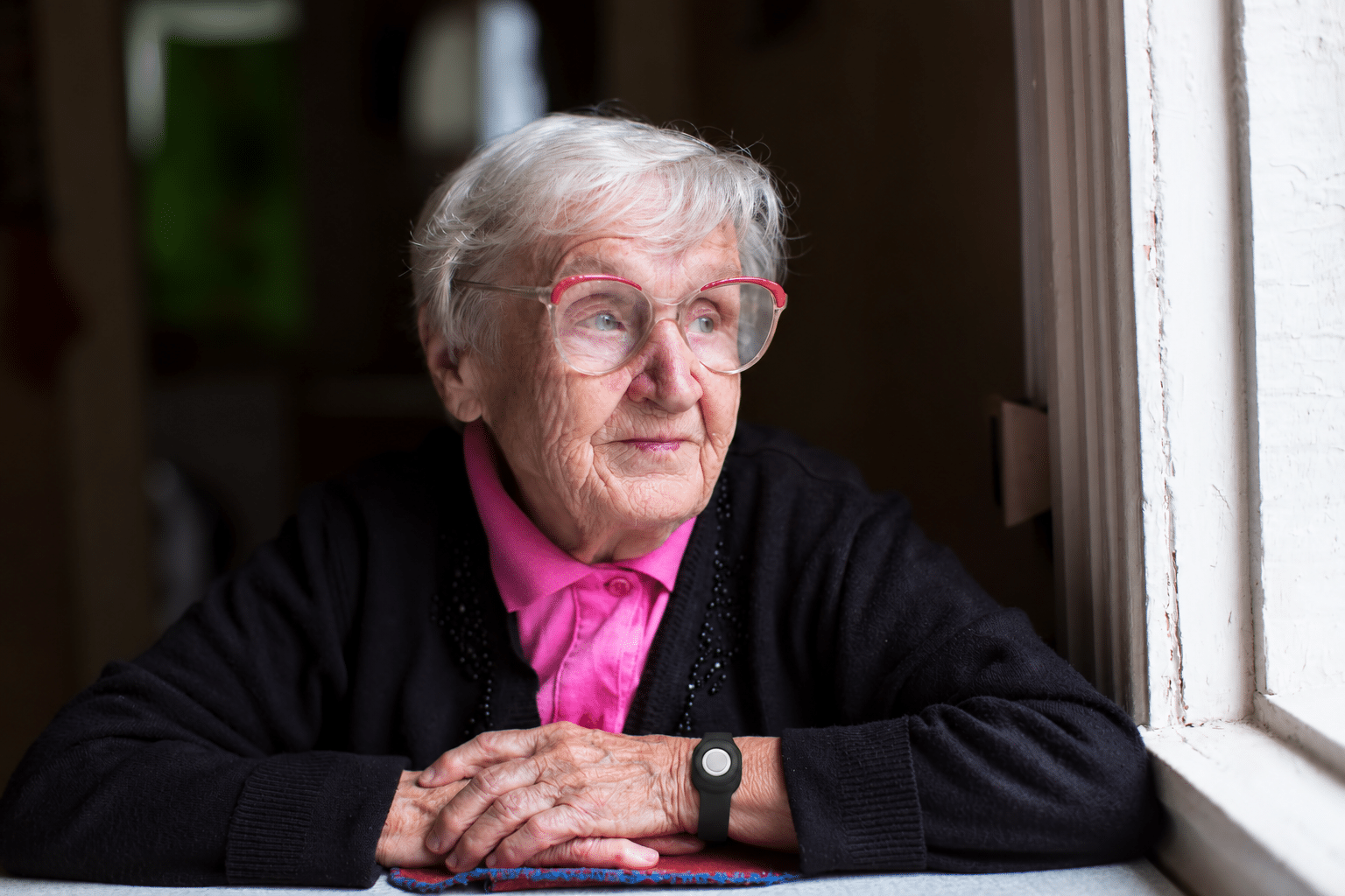 Elderly woman wearing a medical alert button for “I’ve fallen and I can’t get up” emergencies