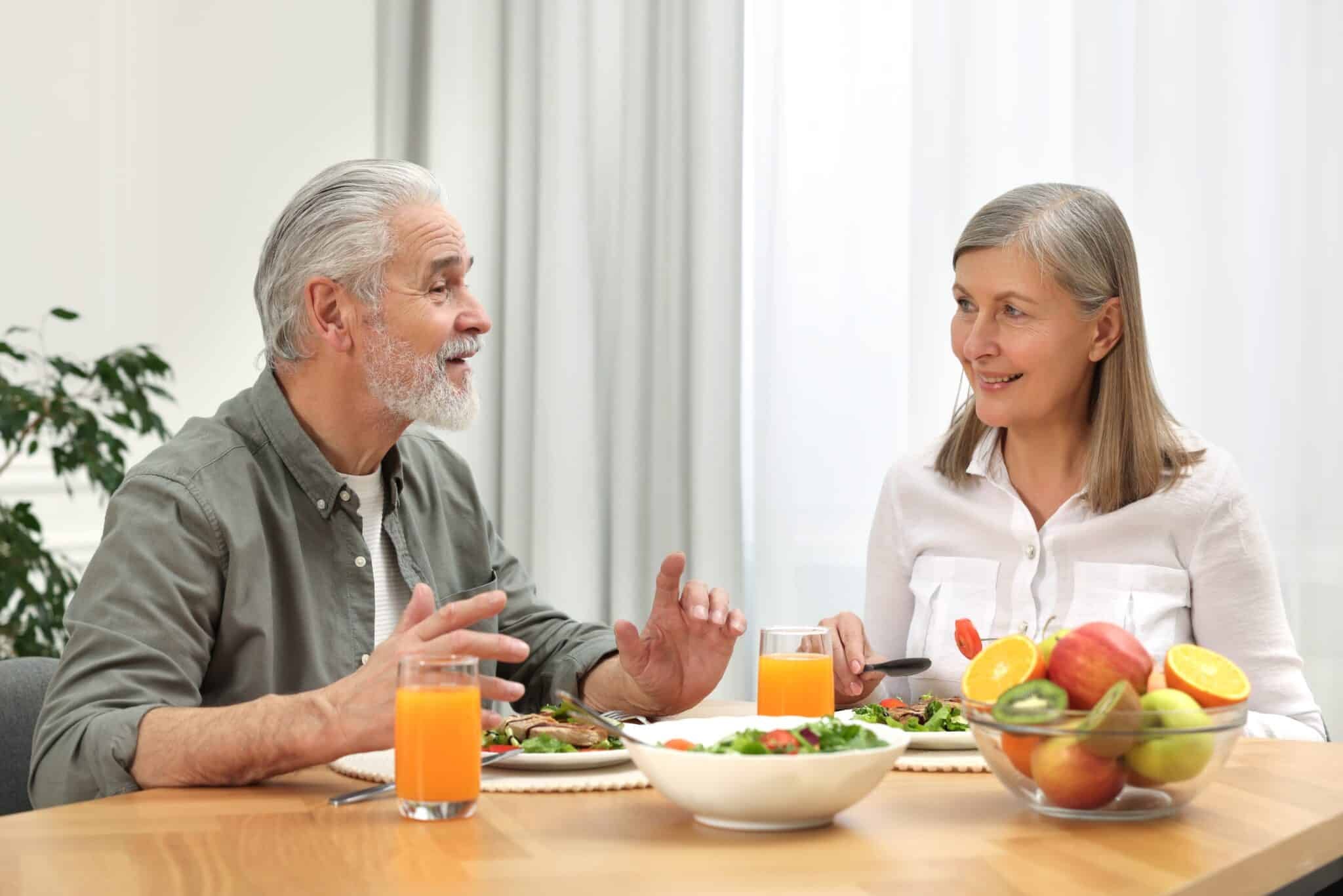 Older couple enjoying a healthy meal while discussing if cheese is bad for cholesterol.